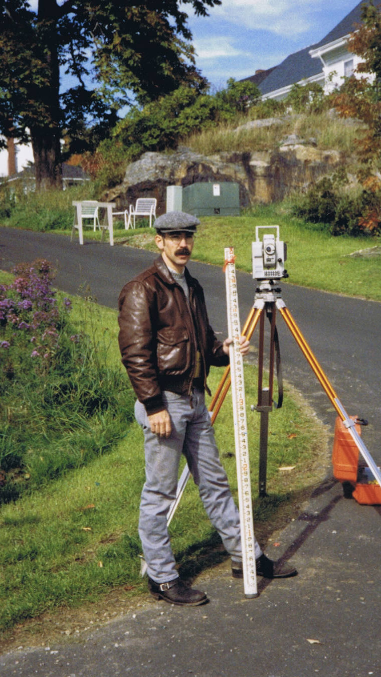 Donald R. Richards working in the field with a transit and level rod