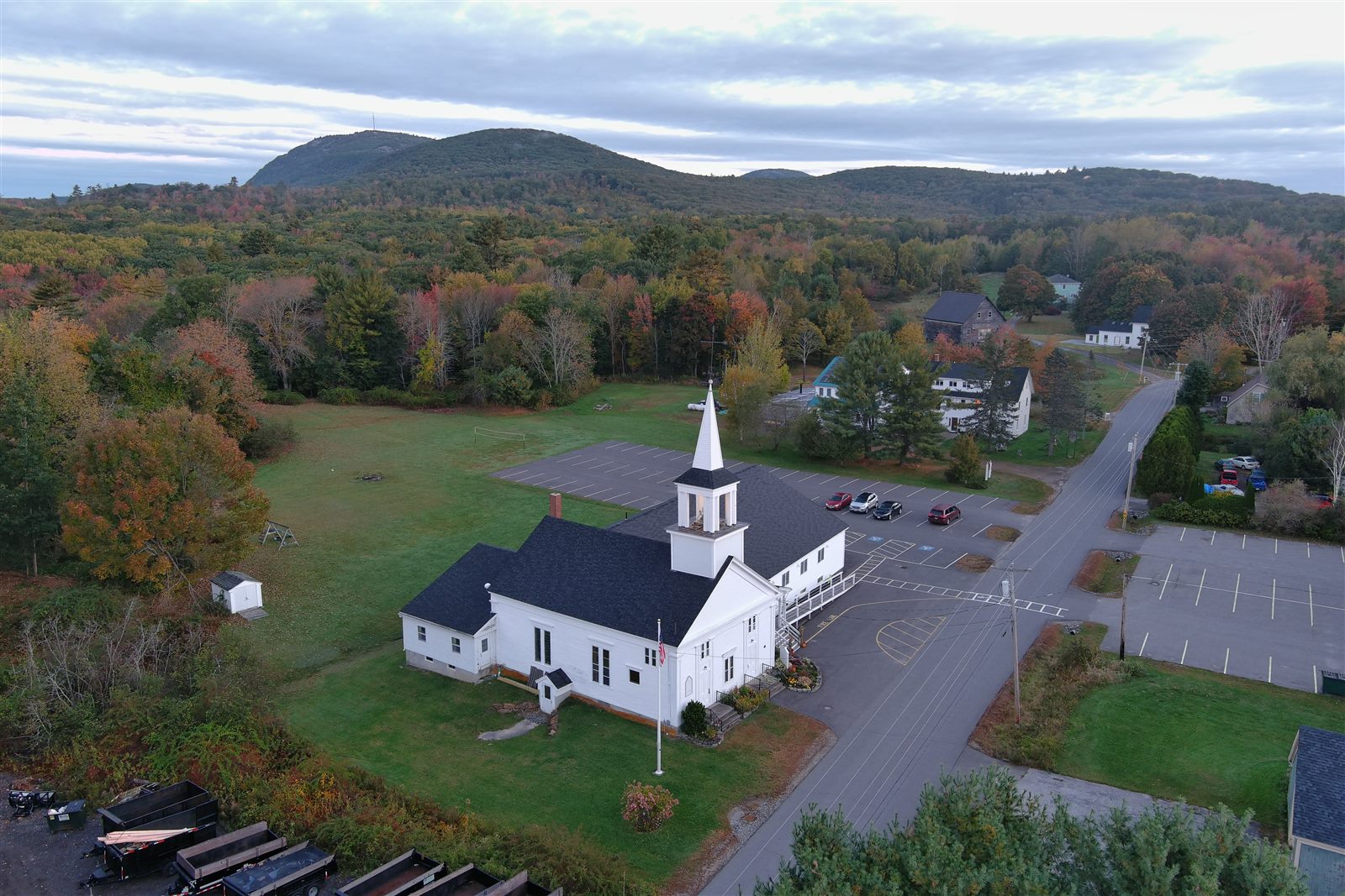 White church and village roads surrounded by autumn trees with hills beyond