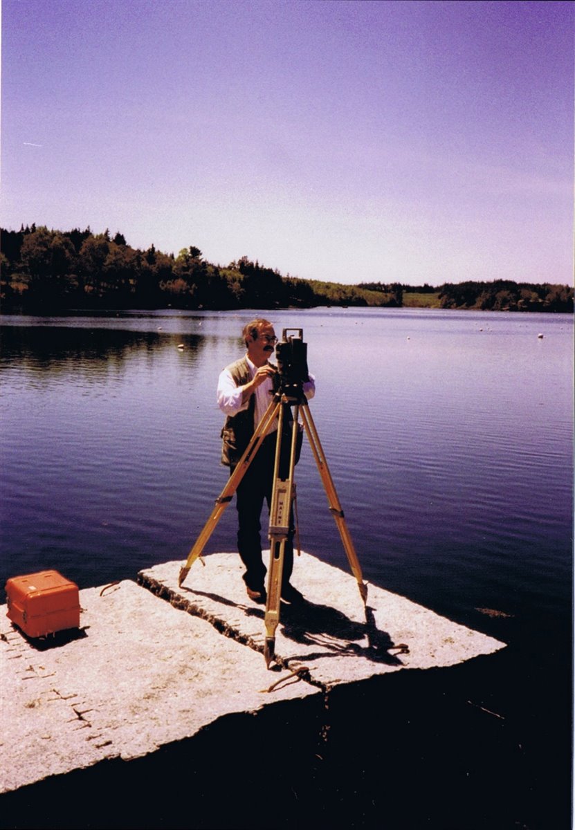 Donald R. Richards surveying from a waterfront ledge